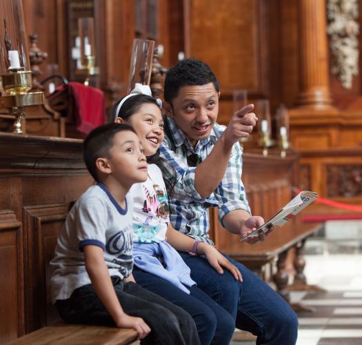 A family in a college chapel, pointing and smiling