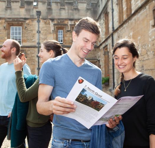 Two people standing in St John's College holdin a brochure