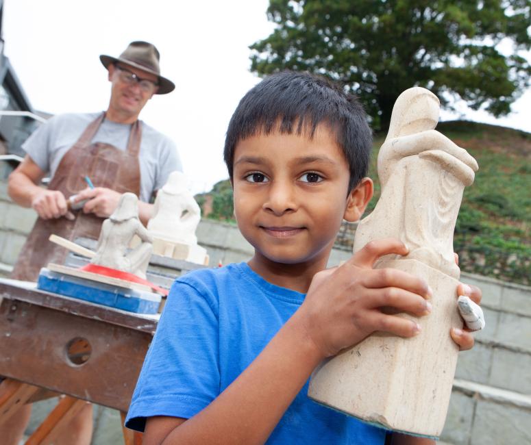 a young boy holding a carved statue at oxford open doors
